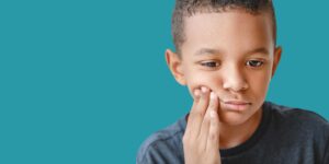 A child holding their cheek in discomfort due to a mild toothache.