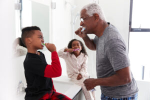 A family brushing their teeth together in the bathroom, promoting healthy dental habits for kids.